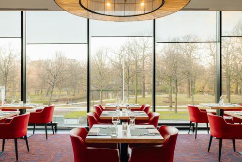 a restaurant with tables and chairs and large windows at Leonardo Hotel Den Haag Babylon in The Hague