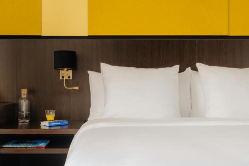 a bed with white pillows and a table with a lamp at Leonardo Oranje Hotel Leeuwarden in Leeuwarden