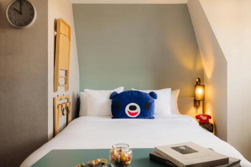 a blue teddy bear sitting on top of a bed at Leonardo Hotel Amsterdam Leidse Square in Amsterdam