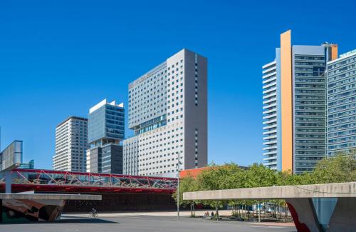 a red bridge in a city with tall buildings at Leonardo Royal Hotel Barcelona Forum in Barcelona