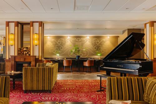 a hotel lobby with a piano and a bar at Leonardo Oranje Hotel Leeuwarden in Leeuwarden