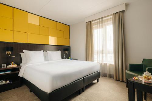 a hotel room with a large bed and a chair at Leonardo Oranje Hotel Leeuwarden in Leeuwarden