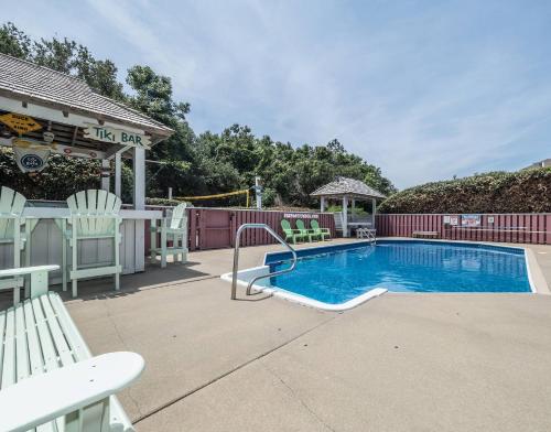 a swimming pool with chairs next to a building at Raspberry Duck - Duck Landing, 525 Yds to Beach, Pool, Tiki Bar, Hot Tub, Close to Downtown in Duck