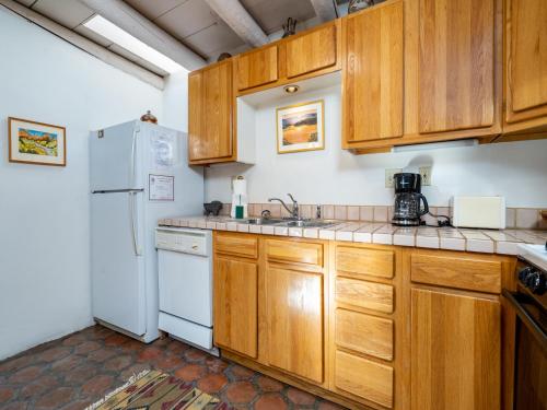 a kitchen with wooden cabinets and a white refrigerator at Casita Don Manuel in Santa Fe