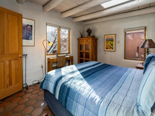 a bedroom with a bed and a desk and windows at Casita Don Manuel in Santa Fe