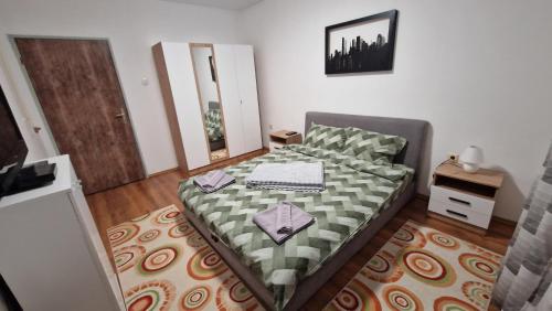 a bedroom with a bed with a green and white blanket at Apartman Dunja in Ruma