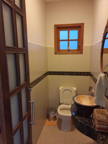 a bathroom with a toilet and a sink and a window at Sítio Ubaitaba in Boituva