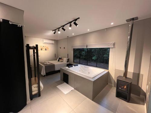 a bathroom with a tub and a sink and a bed at RASTRO Cabins in Restinga Sêca
