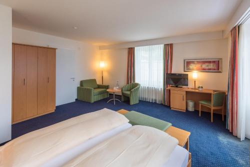 a hotel room with a large bed and a television at Parkhotel Gunten – Beach & Spa in Gunten