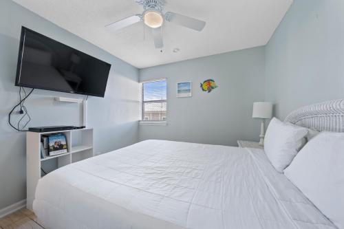 a white bedroom with a large white bed and a flat screen tv at Sea Breeze 316 by Vacation Homes Collection in Gulf Shores