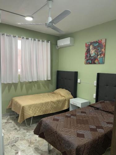 a bedroom with two beds and a ceiling fan at CASA DE LA ABUELa in Colima