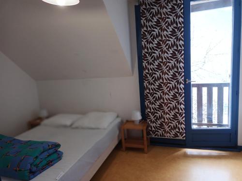 a bedroom with a bed and a large window at Maison dans un chalet en bordure de lac in Loudenvielle