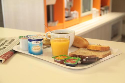 a plate of food with toast and a glass of orange juice at Premiere Classe Soissons in Soissons