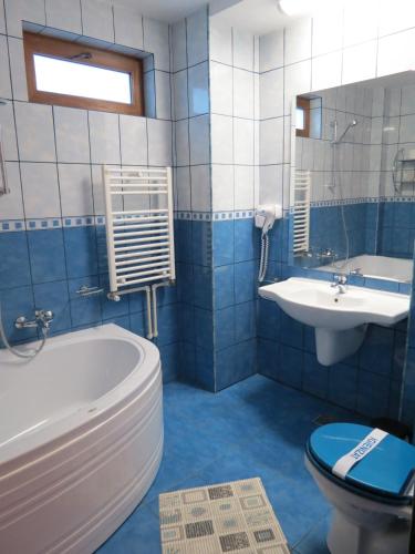 a blue and white bathroom with a tub and a sink at Vila Piano in Buşteni