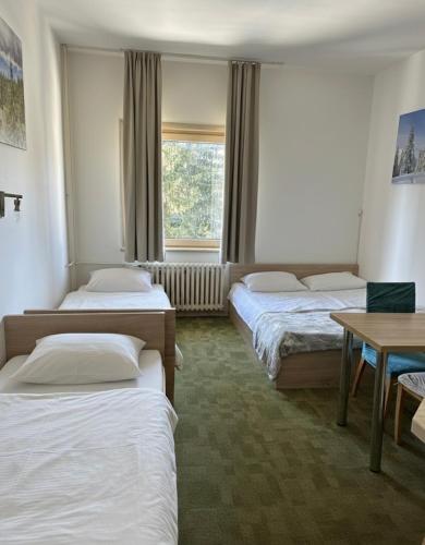 a room with three beds and a table and a window at Apartments Konaci Kopaonik in Kopaonik