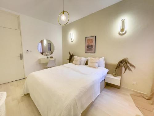 a white bedroom with a large bed and a mirror at Bohemian & White Getaway Zone4 in Abidjan