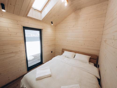 a bed in a wooden room with a window at Zarichna Cottage in Podgorodtsy