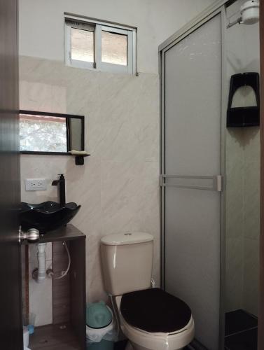 a bathroom with a toilet and a sink and a shower at Mi Cabaña in Nimaima