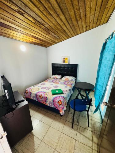 ein Schlafzimmer mit Bett, Tisch und Fernseher in der Unterkunft Casa Osiris in Cali