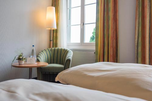 a hotel room with a bed and a chair and a table at Parkhotel Gunten – Beach & Spa in Gunten
