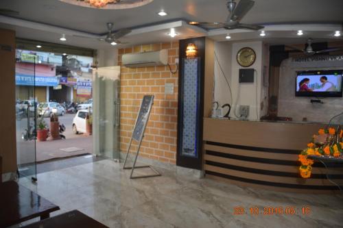 a restaurant with a counter and a clock on the wall at Hotel Vishnu Vilas in Rewa
