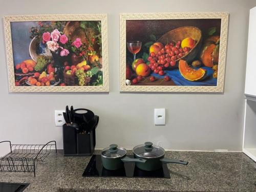 two paintings of fruits and vegetables on a wall at Flat aconchegante em Recife in Recife
