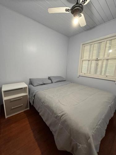 a white bedroom with a bed and a window at Xangri-lá Beach House in Xangri-lá