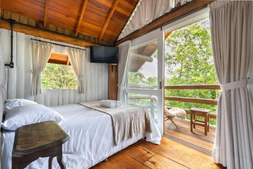 a bedroom with a bed and a large window at Pousada Parador 33 in Biguaçu