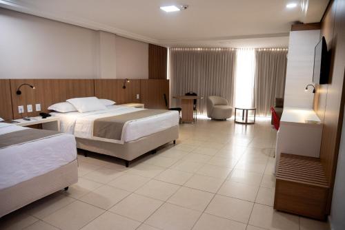 a hotel room with two beds and a desk at Golden Ville Hotel in Marabá