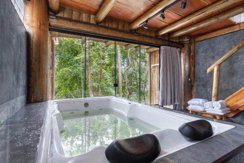 a bath tub in a room with a large window at Pousada Parador 33 in Biguaçu