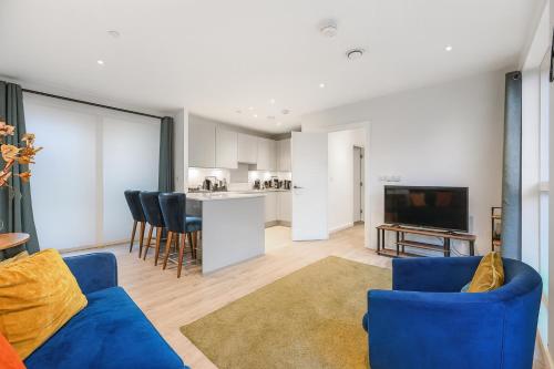 a living room with a blue couch and a kitchen at Executive 3-Bed 2-Bath Apartment Central London in North Woolwich