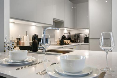 a kitchen with two wine glasses and plates on a counter at Executive 3-Bed 2-Bath Apartment Central London in North Woolwich