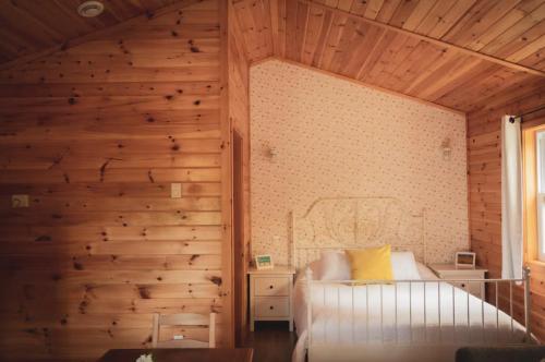 a bedroom with wooden walls and a bed and a window at Lawrencetown Lodge - The Pine 2 Bed Room in Three Fathom Harbour