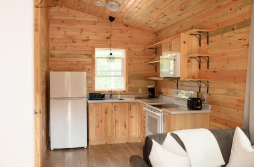 a kitchen with a white refrigerator and wooden walls at Lawrencetown Lodge - The Pine 2 Bed Room in Three Fathom Harbour