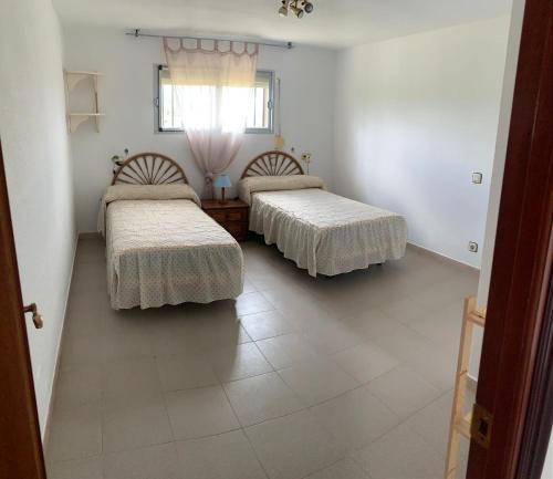 two beds in a room with white walls and tile floors at Casa familiar La Cabra in Talavera de la Reina