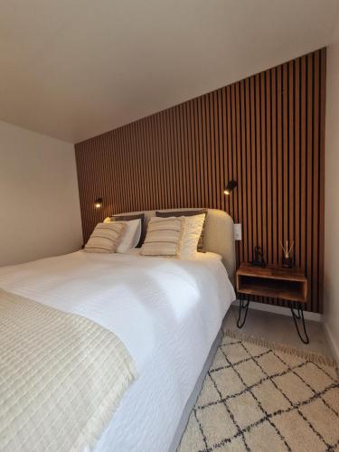 a bedroom with a white bed and a wooden wall at Alba Odeceixe - casa aurea in Odeceixe
