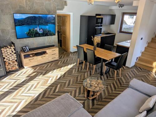 a living room with a television and a table and chairs at MY TIME BLED Holiday House with sauna in Zgornje Gorje