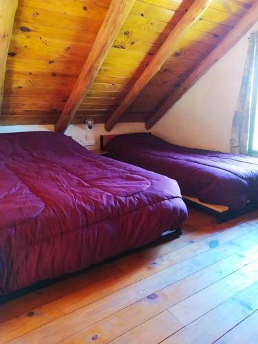 two beds in a room with wooden ceilings at Cabaña La Escondida in Villa de la Quebrada
