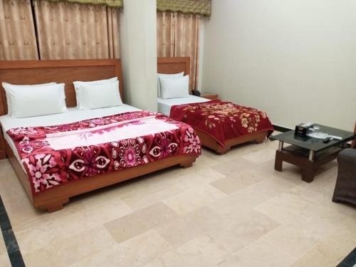 a bedroom with two beds and a table at Sunrise BnB in Karachi