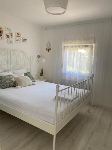 a white bed in a white bedroom with a window at Vikendica Fruška lipa in Čortanovci