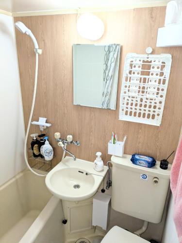 a bathroom with a toilet and a sink and a mirror at エルビスコート井尻101号 in Morooka