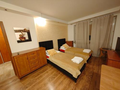 two beds in a room with wooden floors at Vistula Home in Płock