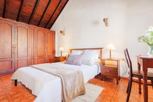 a bedroom with a white bed and a wooden cabinet at Casa Petra - Traditional Canary House in Güimar