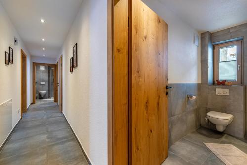 a bathroom with a toilet and a wooden door at Ferienhaus Leo in See