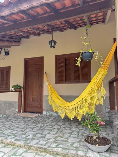 a yellow hammock hanging from the side of a house at Chalé aconchegante em Resende in Resende
