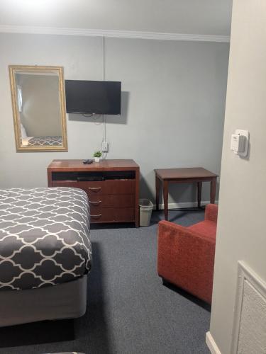 a bedroom with a bed and a dresser and a mirror at Southland Motor Lodge Hotel in Woodhaven