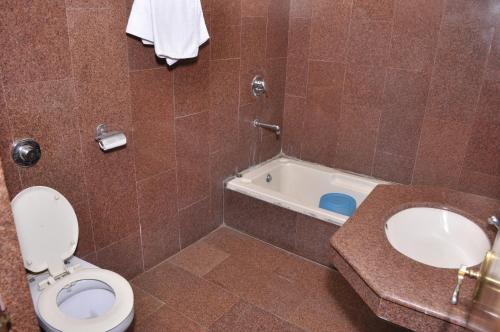 a bathroom with a toilet and a bath tub at Hotel Pratiksha in Morādābād