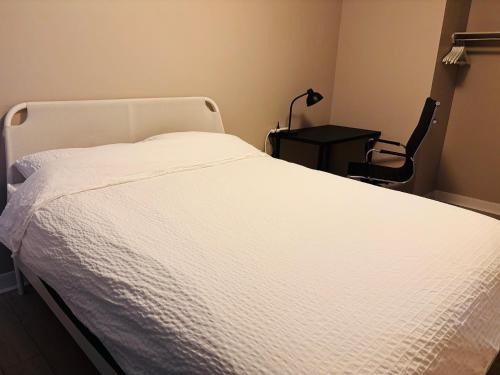 a white bed in a bedroom with a lamp on a table at 6th Floor 2-Bedroom Condo with Parking in Calgary