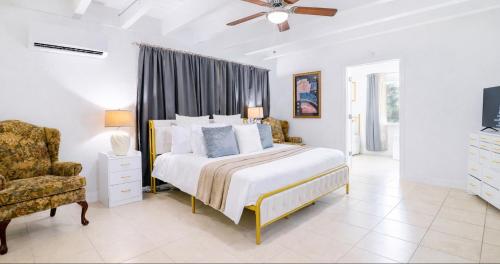 a white bedroom with a bed and a chair at Family-Friendly Beach Home in West Palm Beach, FL in West Palm Beach