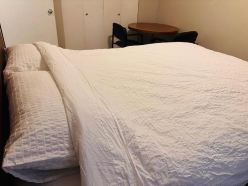 a bed with a white blanket on top of it at Cozy 2-Bedroom Condo with Parking in Calgary